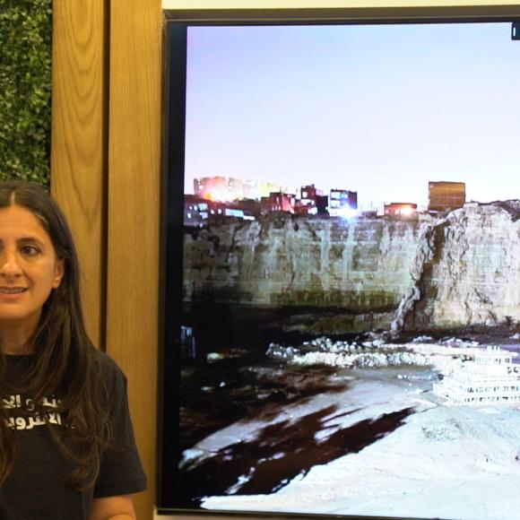 A woman is standing next to a screen