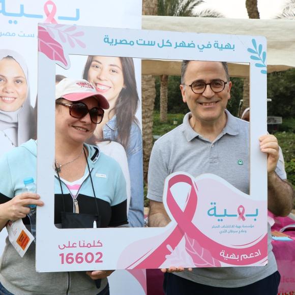 A man and a woman smiling and holding a frame that reads بهية في ضهر كل ست مصرية، ادعم بهية