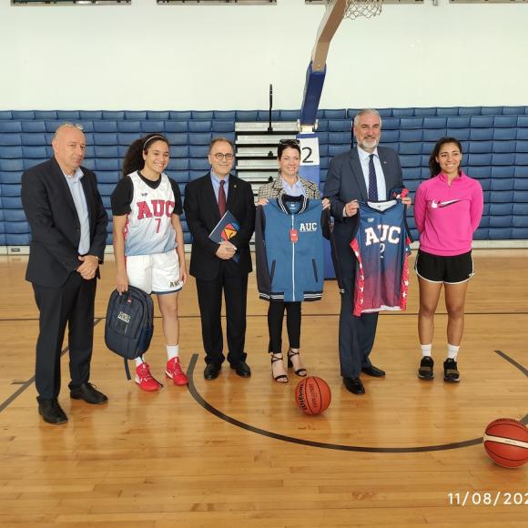 Group photo of three men, a woman and two female athletes, AUC