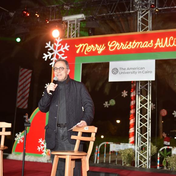 Man talking into a microphone, Merry Christmas AUCians, The American University in Cairo