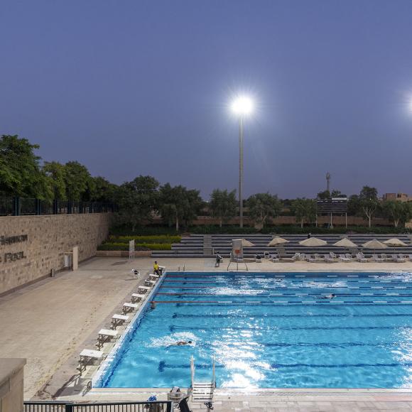 A view of an athletic swimming pool with a row of chairs next to it