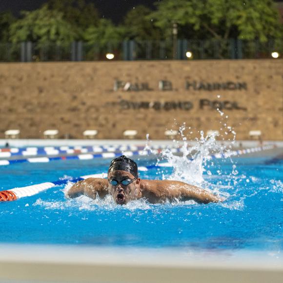 Boy swimming in an athletic swimming pool wearing a swimming cap and goggles