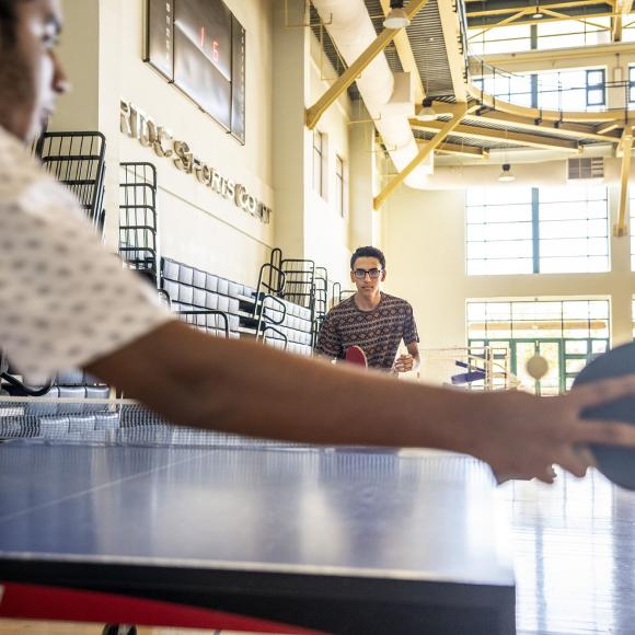 Two male students holding rackets in their hands and playing table tennis in Artoc Sports Court.