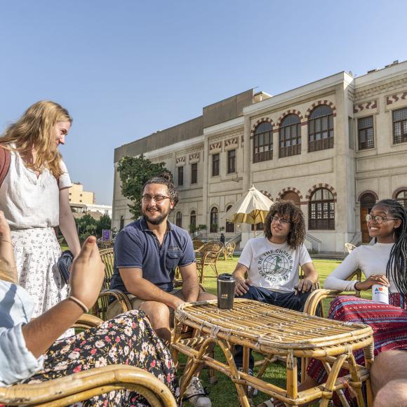 A group of international students sitting around a table in a garden 
