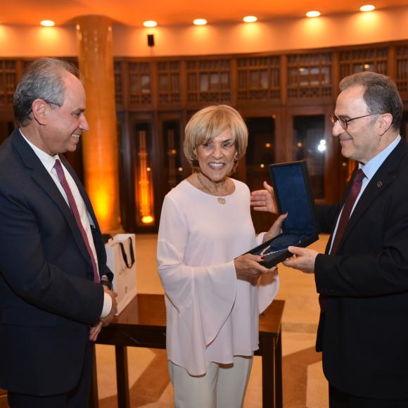 A woman receiving an award from AUC President Ahmed Dallal and shaking hands