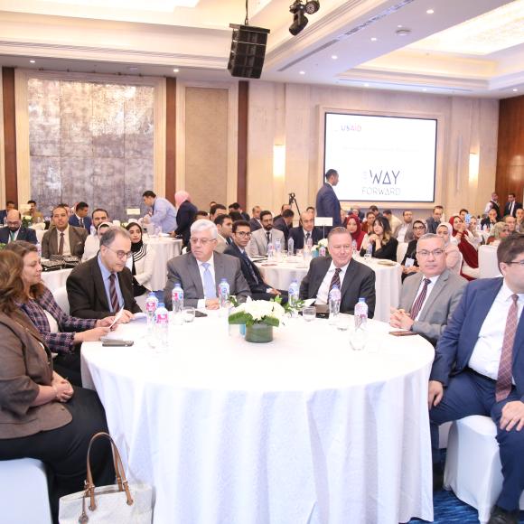 A group of people sitting around a table during an event in a hall