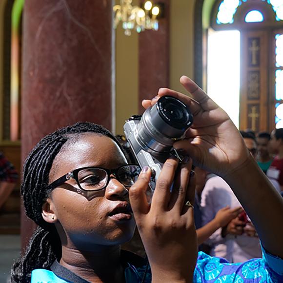 Girl with braids holding a camera inside a mosque taking pictures