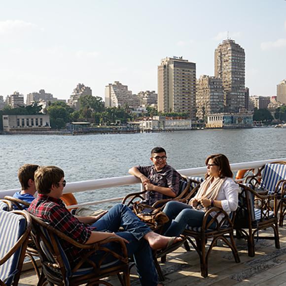 Group of boys and girls sitting on chairs in a cafe by the nile
