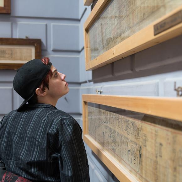 A boy wearing a cap looking at a a wall 