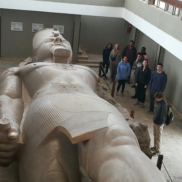 A large statue in a museum with people standing around it 