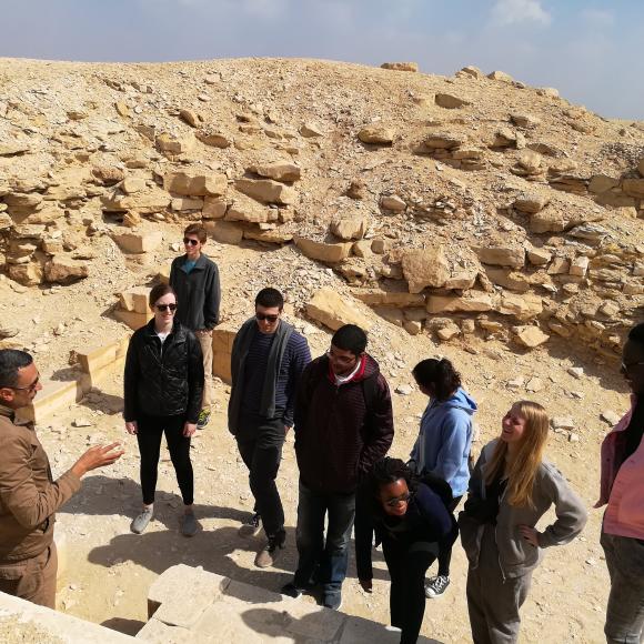 A group of men and women standing in a desert