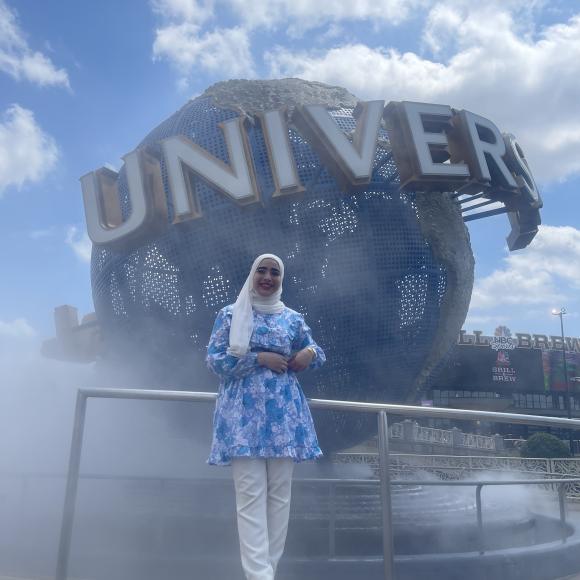 A veiled female student standing in front of the Universal Studios globe