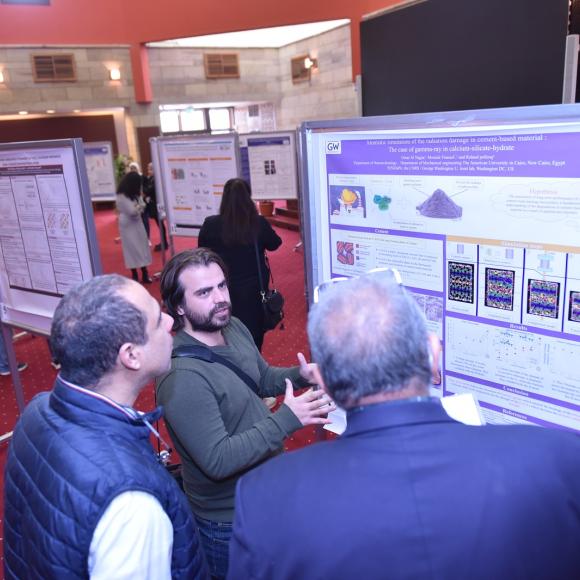 A man talking to two man in front of a board