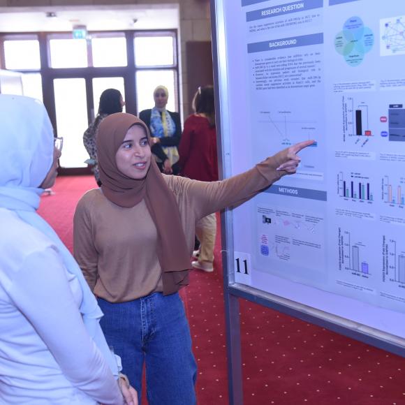 A woman talking to another woman in front of a board