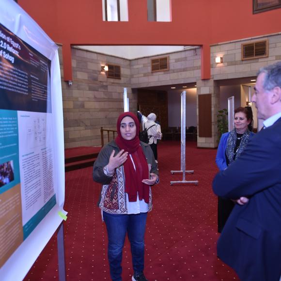 A woman talking to a man and a woman in front of a board