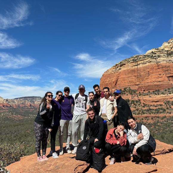 a group of students in front of a green area and mountains
