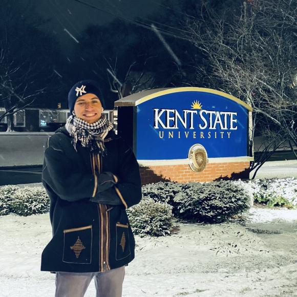 A boy standing infront of a university sign in the snow