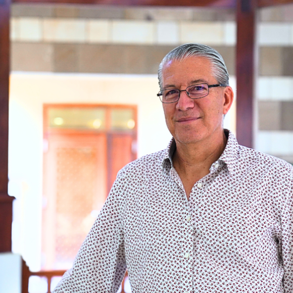 Man standing, wearing a shirt and glasses and smiling