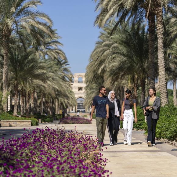 one boy and three girls walking on campus in university gardens