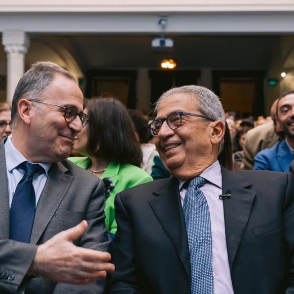 Two men talking sitting together and sitting in a crowd