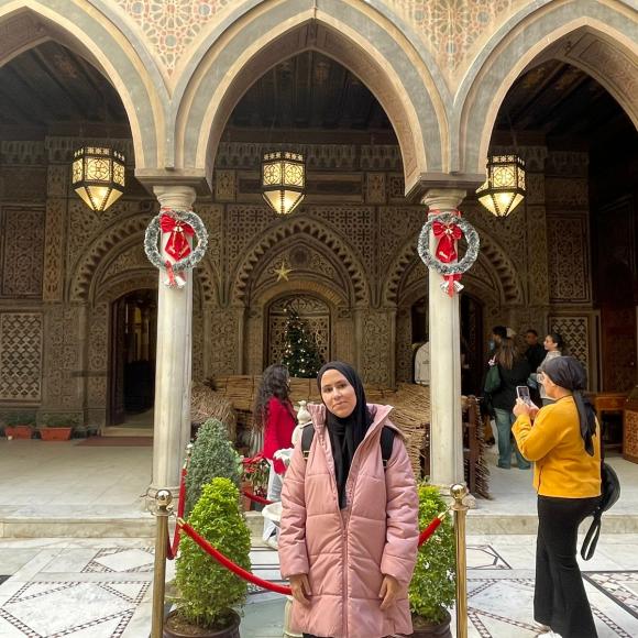 A student poses in front of arched architecture