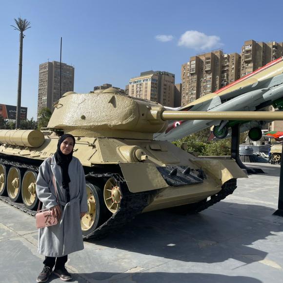 A student stands beside a tank