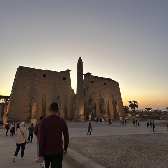 People stroll around a historic site at sunset