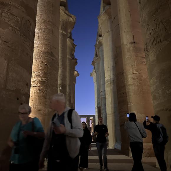 People walk through a corridor of enormous pillars