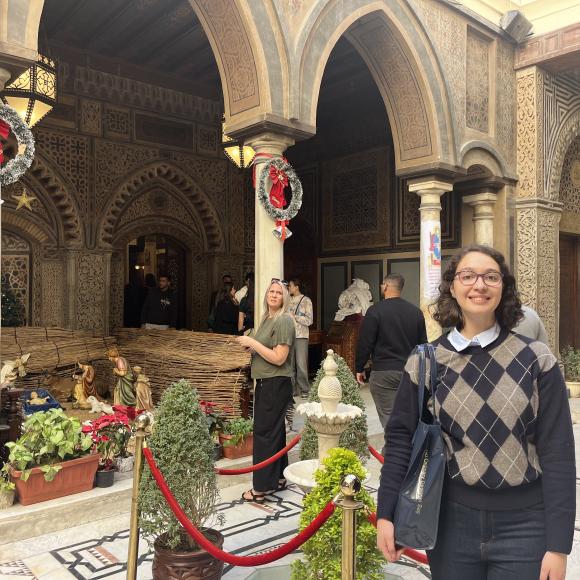 Student smiles in front of arched architecture