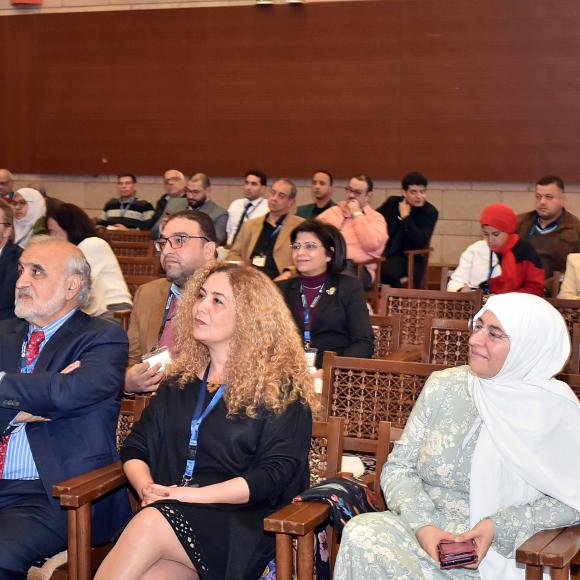 a group of people sitting in a hall listening to a speech