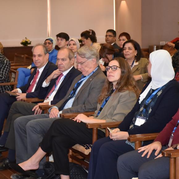 a group of people sitting in a hall listening to a speech