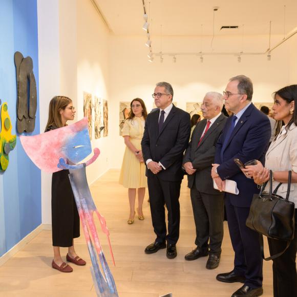 Men and women are viewing a piece of art