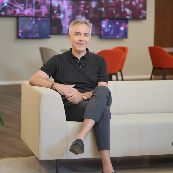 a man with white hair sitting cross legged on a white couch