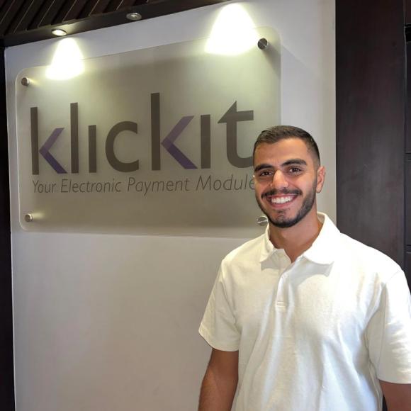 a student wearing a white tshirt with short black hair and a short beard and mustache