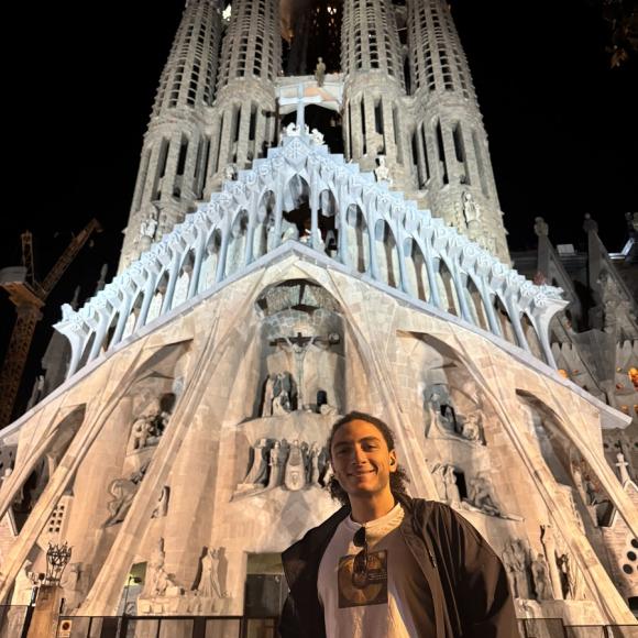 A male is smiling and standing in front of an ancient church