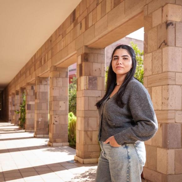 A female is standing, she has her hands in her pockets