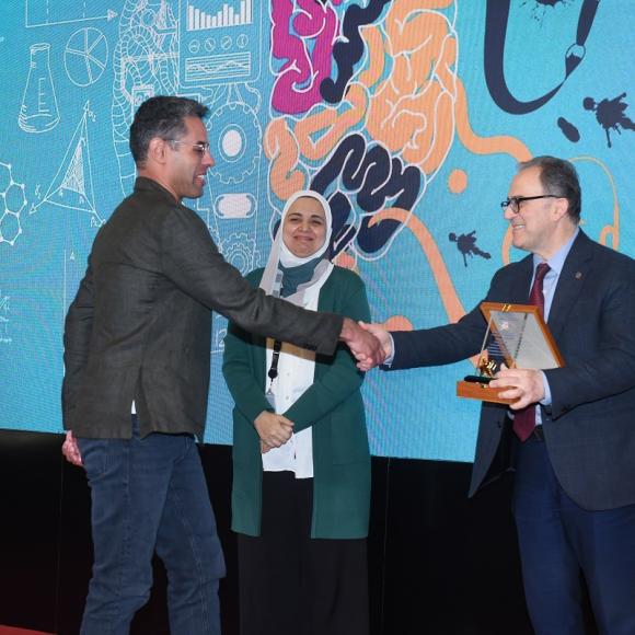 A man is giving another man an award. There is a veiled woman next to them