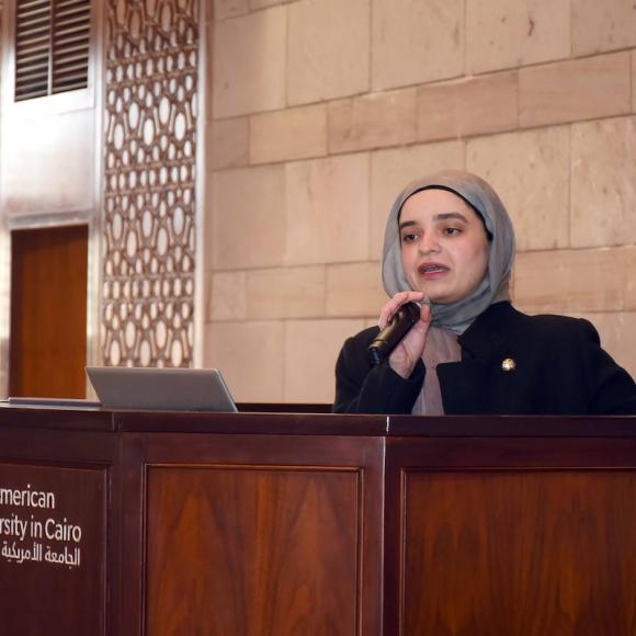A female talking in a microphone behind a podium.