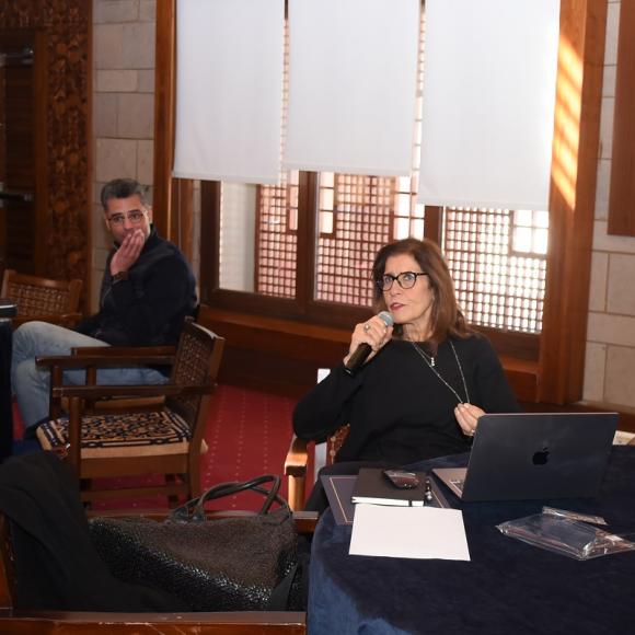 A woman is talking into a microphone. She is sitting next to a woman and a man