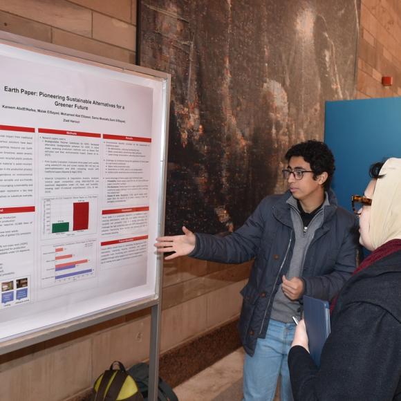 Two males and a female are standing in front of a board and talking