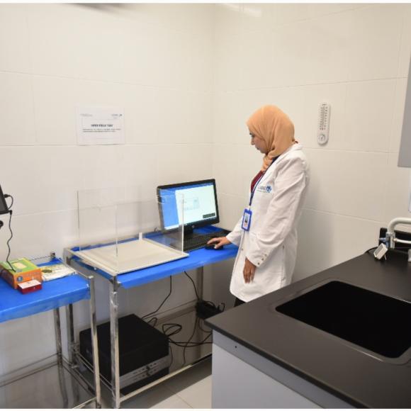 a veiled woman wearing a white coat in a lab working on a computer