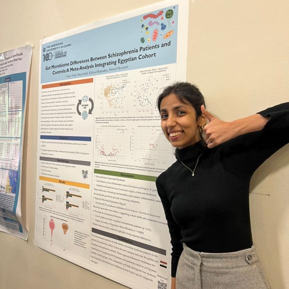 Husn standing next to a banner holding a thumbs up