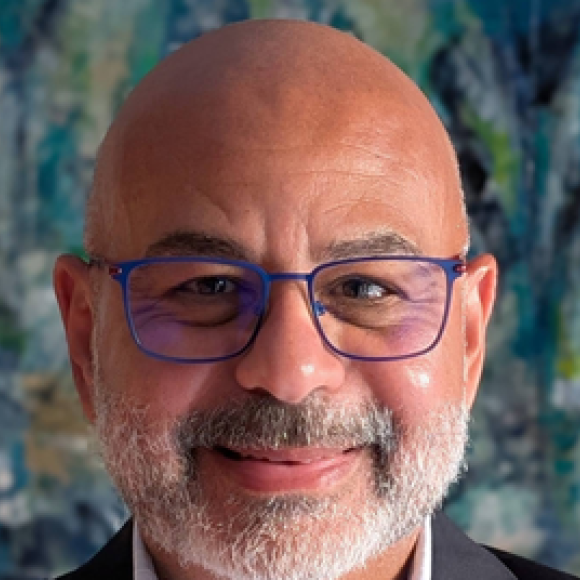a headshot of a bold man with white beard wearing glasses