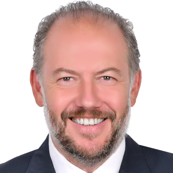 a headshot of a man wearing a black suit and white shirt with grey hair and grey beard