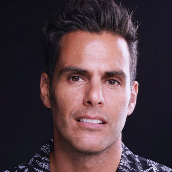 a headshot of a man with short brown hair smiling