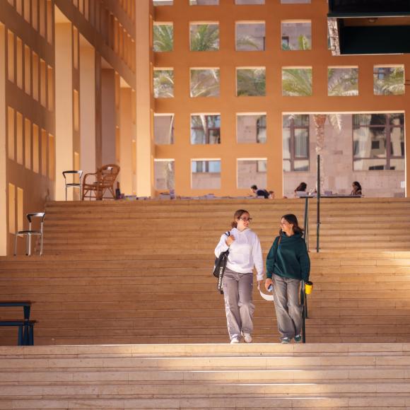 two girls walking down the stairs behind the auc library building