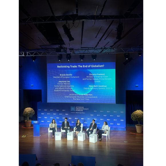 A group of panelists sitting on separate chairs onstage