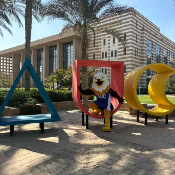 auc mascot sitting in the AUC monogram in the gardens