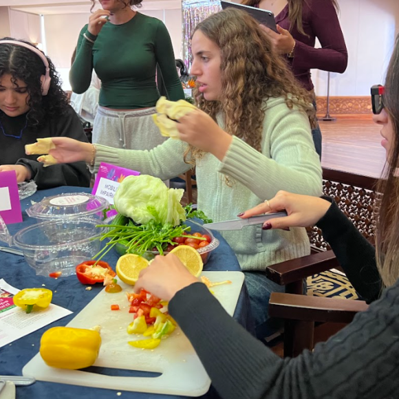 Students with simulated audio and physical impairments making salad