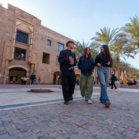 A male and two females are walking and smiling